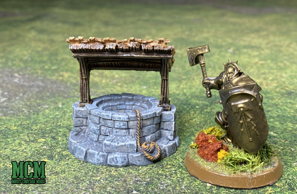 Monster Fight Club's Village Well along side an Age of Sigmar Miniature